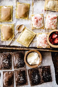 some desserts are sitting on a table with spoons and bowls full of powdered sugar