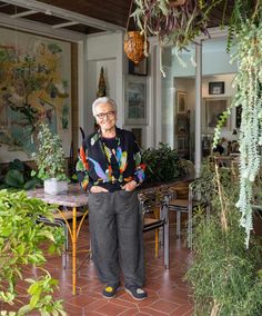 an older woman standing in front of a table with plants on it and the caption inside the joyful lombaby home of rosita missonii