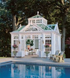 a white house with a green roof next to a swimming pool