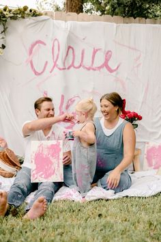 a man and woman are sitting on the grass with pink paint all over their body