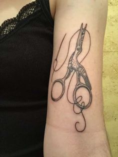 a woman with a tattoo on her arm holding a pair of scissor's