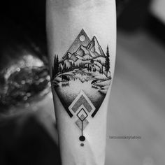 a black and white photo of a mountain landscape tattoo on the right forearm, with an arrow in the middle