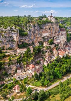 an aerial view of a small village on the side of a cliff with trees in front of it