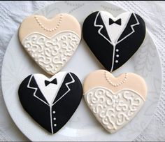 four decorated cookies in the shape of hearts with tuxedo and bow ties on a plate