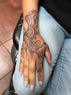 a woman's hand with an intricate tattoo design on her left wrist and fingers