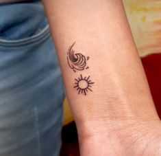 a small tattoo on the wrist of a woman's left arm, with sun and moon