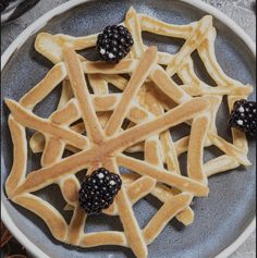 a plate with waffles and blackberries on it next to some cinnamon sticks