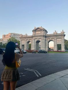 a woman taking a photo of the arch of triumph