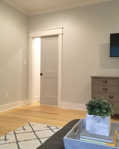 an empty living room with white walls and wood floors is pictured in this image, there is a television on the wall