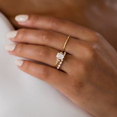 a woman's hand wearing a gold ring with three stones on the middle and one stone in the middle