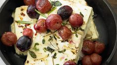 a pan filled with cheese and olives on top of a table