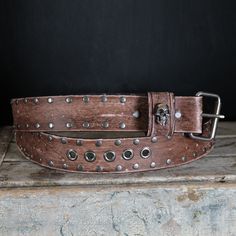 Skull leather belt, studded.  . Our Aging / Relic process is carefully made by Hand, from the leather to the Hardware, giving this unique Strap Authenticity and the Style we love like it  already lived for decades.  Features: Designed with Chicago screws that allows you to easily remove and replace the Buckle.  .Leather: 7-8oz (4-5 mm thick) premium vegetable tan leather, great thickness for durability and comfort that will age beautifully with time.      .Width : 2 inches wide. .Color: Aged light Brown . hand dyed with a rich Finish  .Hardware and studs: Antique Nickel. .Size:     -PLEASE CHOOSE YOUR SIZE VERY CAREFULLY -- .Our recommendation and most accurate way to Choose your size as shown in the Picture.  Our mission is for you to pick the correct size and enjoy your new belt.  Please Adjustable Leather Belt Buckles With Rivets, Rugged Leather Belt Buckle In Distressed Brown, Vintage Leather Belt Buckles With Rivets, Comfortable Fall Outfits, Vintage Distressed Brown Leather Belt, Vintage Brown Belts With Rivets, Adjustable Brown Belt With Rivets, Rustic Brown Hand-tooled Belt, Vintage Brown Hand-tooled Belt Buckle