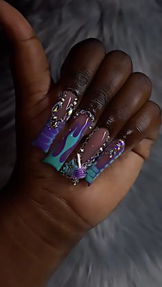 a woman's hand with purple and blue nail polishes on her nails, while holding