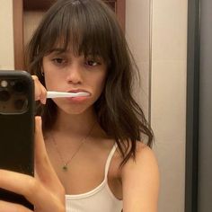 a young woman brushing her teeth with an electric toothbrush in front of the mirror