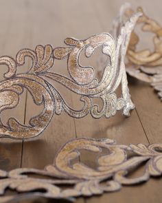 a silver and gold tiara sitting on top of a wooden floor next to another tiara