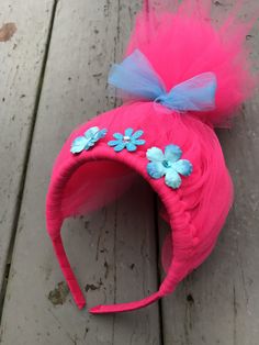 a pink headband with blue flowers on it sitting on a wooden floor next to a piece of wood