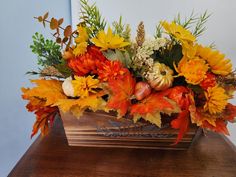 a wooden table topped with a vase filled with orange and yellow flowers on top of it