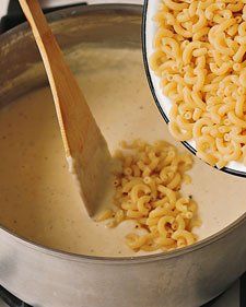 macaroni and cheese is being stirred in a pot with a wooden ladle