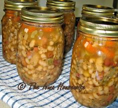 four jars filled with food sitting on top of a blue and white checkered cloth