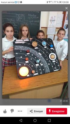 two girls and one boy are standing in front of a blackboard with the solar system on it