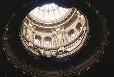 looking up at the ceiling in an old building with round windows and statues on it