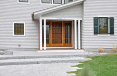 a large gray house with green shutters on the front door and steps leading up to it