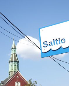 a blue and white sign hanging from the side of a building next to power lines