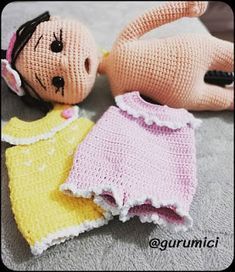 two crocheted dolls laying on the floor next to each other, one wearing a yellow dress