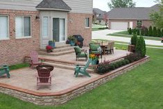 an outdoor patio with chairs and tables in front of a brick building on the grass