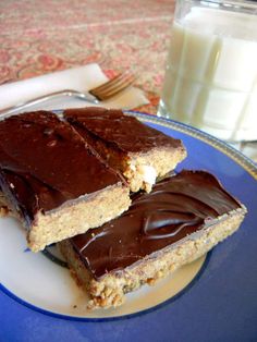 two pieces of chocolate and peanut butter bars on a plate with a glass of milk