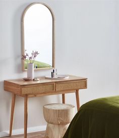 a wooden table with a mirror on it and a stool next to it in front of a bed