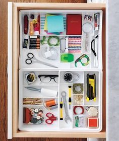 an open drawer with various items in it, including scissors and other office supplies inside