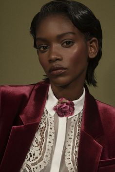 a woman in a red jacket and white shirt with a flower on her lapel