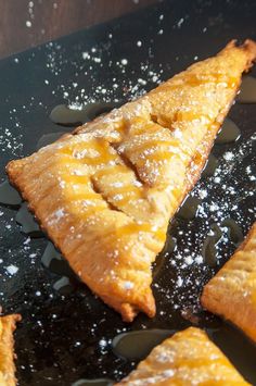 some food that is laying on a black plate with powdered sugar and water around it