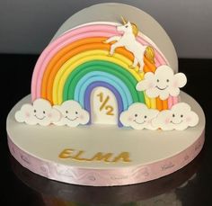 there is a cake that has a unicorn on it and rainbows in the background