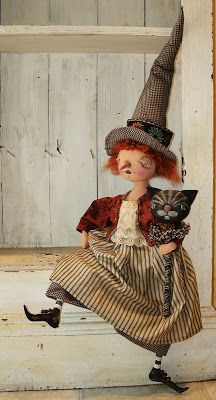 a doll dressed as a witch holding a cat