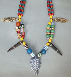 a multicolored beaded necklace with two metal scissors and a leaf charm hanging from it