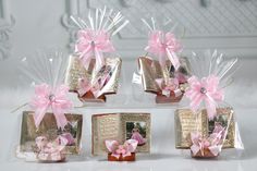 four small gift bags with pink bows and ribbons on them, sitting on a table