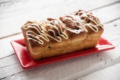 a cinnamon roll with icing on a red plate