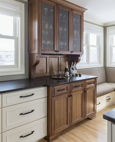 a kitchen with wooden cabinets and black counter tops next to a window filled with wine glasses