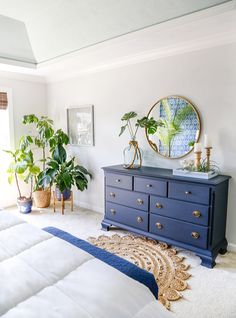 a blue dresser in a white bedroom with potted plants