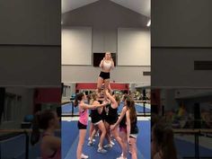 a group of young women standing on top of each other in a gym together,