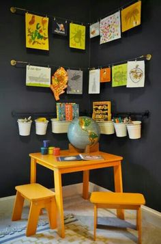 a child's table and chair in front of a wall with pictures on it