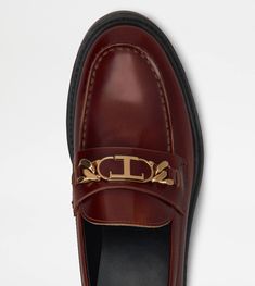 Loafers in refined leather with penny bar, metal T Chain accessory and rubber outsole with embossed rubber pebbles. Formal Leather Loafers With Metal Logo, Brown Loafers With Metal Feet For Work, Luxury Leather Loafers With Leather Footbed For Formal Occasions, Luxury Formal Loafers With Leather Footbed, Elegant Leather Loafers With Metal Logo, Luxury Wingtip Loafers For Work, Luxury Workwear Moccasins With Rubber Sole, Luxury Leather Footbed Loafers For Semi-formal Occasions, Luxury Semi-formal Loafers With Leather Footbed