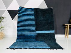 a blue and black rug sitting on top of a white floor next to a chair