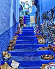 blue painted steps lead up to an alleyway with pictures on the walls and floor