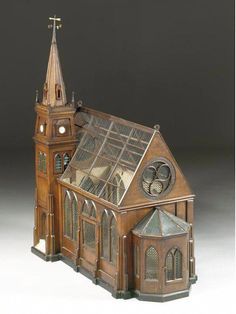 a wooden model of a church with a steeple and clock on the top floor