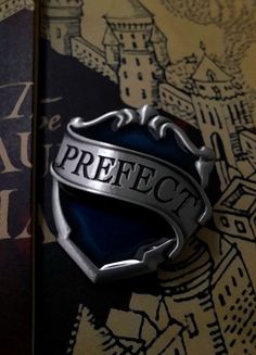 a book with the title perfect written on it next to a harry potter badge and hogwarts crest