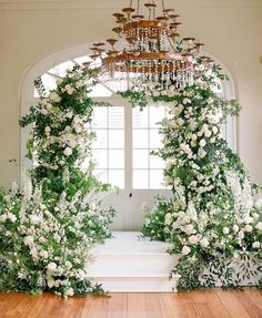 an archway decorated with white flowers and greenery