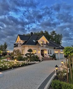 a large white house sitting on top of a lush green field under a cloudy sky